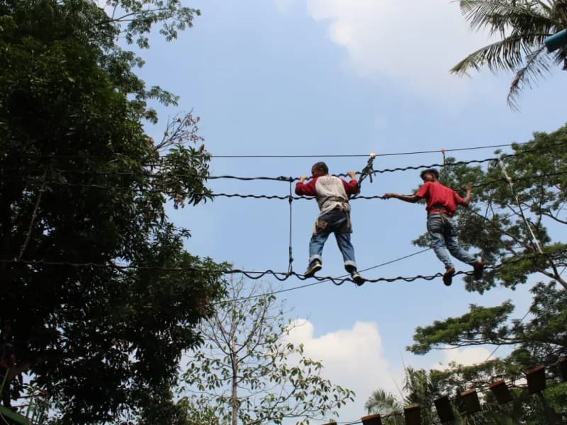 Dua siswa berpengaman lengkap meniti jembatan tali pada kegiatan outbound