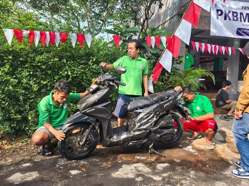 Tiga siswa menyabuni sebuah sepeda motor di halaman depan Karunia Center
